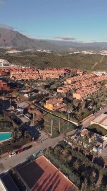 Tepeler ve geniş mavi gökyüzü ile çevrili bir Akdeniz mahallesindeki canlı turuncu villaların hava manzarası. Yüksek kalite 4k görüntü