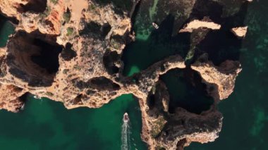 Ponta da Piedades 'in turkuaz sularda eşsiz kaya oluşumları. Manzaralı kemerlerden küçük bir tekne geçiyor, Algarve 'a gidilmesi gereken bir yer. Yüksek kalite 4k görüntü