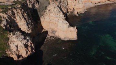 Algarve sahil şeridine geniş bir hava manzarası, engebeli uçurumlar ve sakin, yeşil sular. Huzurlu ve resimli bir seyahat yeri. Yüksek kalite 4k görüntü