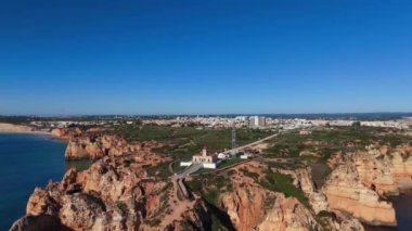 Ponta da Piedades sahil şeridini ve arka planda genişleyen Lagos kasabasını tarıyor. Zümrüt okyanusu bu Algarve mücevherindeki dramatik kayalıklarla buluşuyor. Yüksek kalite 4k görüntü