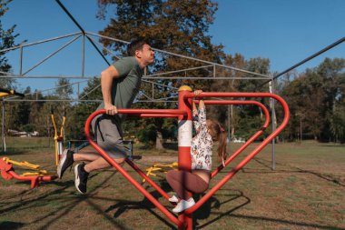 Bir baba ve kız, güneşli bir günde spor yapmak, spor yapmak ve oyun oynamak için açık hava spor ekipmanlarını kullanırken eğlenirler. Yüksek kalite fotoğraf
