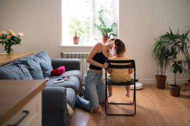 Bir anne genç kızına dikkatlice makyaj yapar ve onu bitki ve doğal ışıkla dolu sıcak bir oturma odasında bir partiye hazırlar. Yüksek kalite fotoğraf