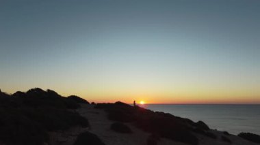 Algarve 'da gün batımı manzarası göz kamaştırıcı, okyanusa bakan siluetli bir figür. Yavaş yaşam ve maceralı van hayat tecrübeleri için mükemmel. Yüksek kalite 4k görüntü