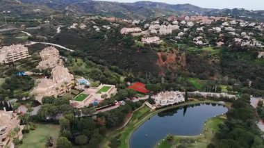 Tepelerle çevrili gölet, golf sahası ve yeşil alanların bulunduğu Akdeniz banliyö mahallesinin tepeden aşağı manzarası. Yüksek kalite 4k görüntü