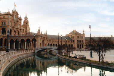 Seville 'deki Espana Meydanı' nda tarihi mimari ve kanal yansıması.