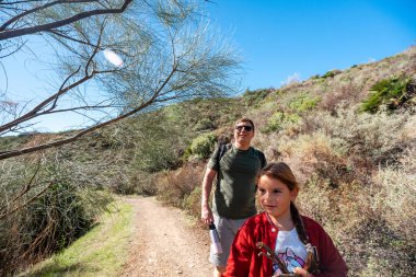 Baba ve kızı güneşli kırsal bölgede yürüyüş yapıyor..