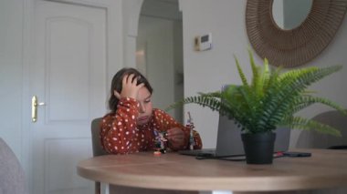 Oturma odasında masanın üzerinde saksı bitkisi olan oyuncak yapmaya odaklanan çocuk..