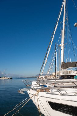 Mavi gökyüzü ve sakin sularla dolu açık bir günde limana yanaşmış lüks yatlar..