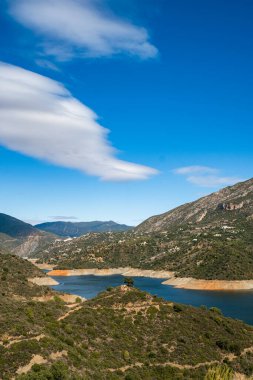 Berrak mavi gökyüzünün altında dingin dağ gölü yuvarlanan tepeler ve yemyeşil.