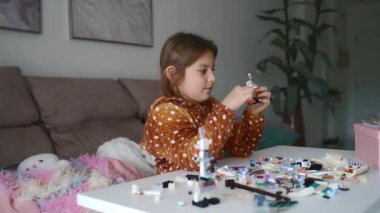 Evde, rahat oturma odasında yaratıcı Lego binasıyla meşgul olan genç bir kız..