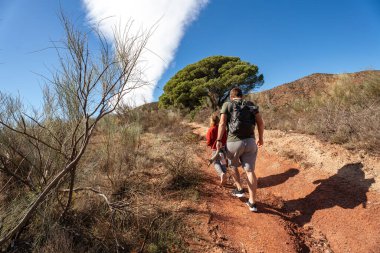 Kafkasyalı yetişkinler ve çocuklar doğada güneşli patikada yürüyüş yapıyorlar..