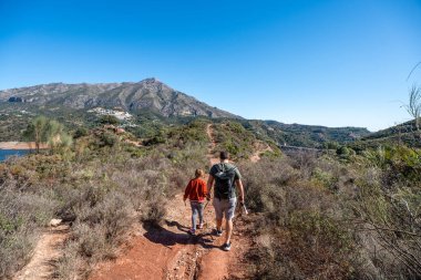 Baba ve kızı dağ manzaralı manzaralı yolda yürüyüş yapıyorlar..