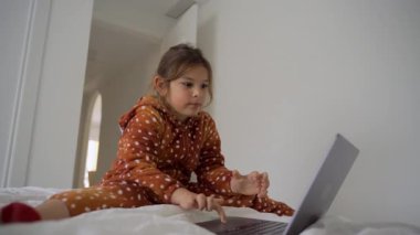 Çocuk rahat yatak odasında dizüstü bilgisayarda yaratıcı öğrenme ve oyun zamanı ile meşgul..