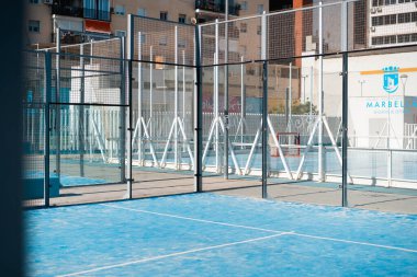 Marbella, İspanya - 1 Mayıs 2025 Sunlit Padel Court şehir binalarıyla çevrili.