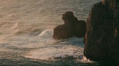 Portekiz, Sagres 'teki Atlantik Okyanusu üzerinde güneş batarken Cape St. Vincent deniz fenerinin çarpıcı güzelliğine tanık olun. Kıyıdaki kayalıkları ve çarpan dalgaları keşfedin..