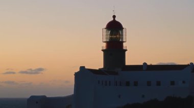 Portekiz, Sagres 'teki St. Vincent Burnu' ndaki deniz fenerinin gün batımının sıcacık parıltısıyla aydınlanan nefes kesici güzelliğine tanık olun. Atlantik Okyanusu üzerinde sakin manzaralar bekliyor..