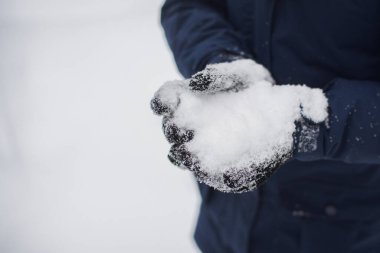 Kışın avucunun içinde kar olan, yalıtılmış kış sporu eldivenine dayanıklı siyah kumaştan bir su görüntüsü..