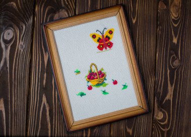 Çerçevedeki kumaşa işlenmiş sepet. Ahşap bir arka planda bir çerçeveye nakış..