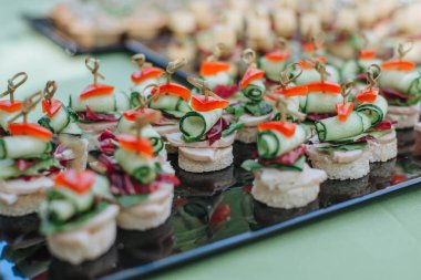 Parmak yiyeceği. Şişte peynir ve domates dilimleri. İtalyan aperatifleri peynirli, kiraz domatesli ve zeytinli siyah tahtada çubuklar, yemek servisi, ziyafet.