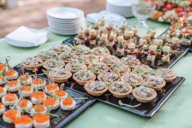 Parmak yiyeceği. Şişte peynir ve domates dilimleri. İtalyan aperatifleri peynirli, kiraz domatesli ve zeytinli siyah tahtada çubuklar, yemek servisi, ziyafet.