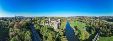 An aerial panorama reveals the majestic Lismore Castle in County Waterford, Ireland, set against a flawless spring sky clipart