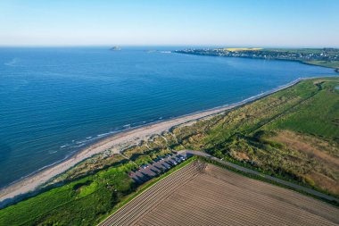 Ballynamona Sahili 'nin ve Ballycotton Körfezi' nin havadan görünüşü, İrlanda 'nın Cork İlçesi, kumlu bir kıyı şeridi, yeşil alanlar, park edilmiş arabalar ve açık bir yaz gününde uzak mesafedeki ikonik Ballycotton Adası..