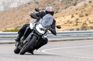 Motosikletli keskin bir viraj alıyor. Fotoğraf 9 Eylül 2020 tarihinde İspanya 'nın Avila ilinin Navalmoral limanında çekildi.
