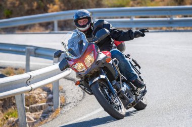 motorcyclist taking a sharp curve on his bike. Photograph taken in the port of Navalmoral, province of the city of Avila, Spain, during the day September 10, 2022