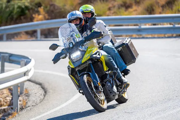 Motosiklet sürücüsü, arka planı doğa ve mavi gökyüzü olan ön planda bir viraj alıyor.