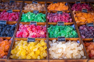 Önplanda, üzerinde ve kırsal ahşap kabın üzerinde şeker bulunan farklı renk ve dokulardan tatlı şekerler sergileniyor.