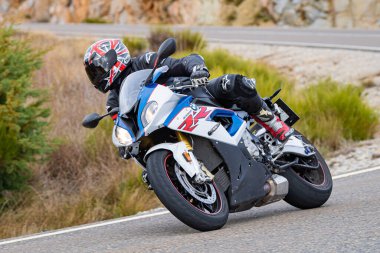 Motorsikletinde oturan bir adam, dağ yolunda keskin bir dönüş yapıyor. Fotoğraf Ağustos 2020 'de Avila şehrinde çekildi.