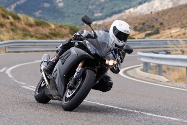 Motorsikletinde oturan bir adam, dağ yolunda keskin bir dönüş yapıyor. Fotoğraf Ağustos 2020 'de Avila şehrinde çekildi.