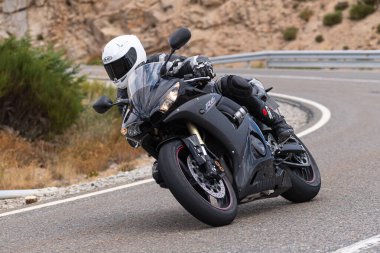 Motorsikletinde oturan bir adam, dağ yolunda keskin bir dönüş yapıyor. Fotoğraf Ağustos 2020 'de Avila şehrinde çekildi.