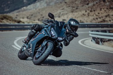 Motorsikletinde oturan bir adam, dağ yolunda keskin bir dönüş yapıyor. Fotoğraf Ağustos 2020 'de Avila şehrinde çekildi.