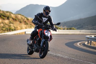 Motorsikletinde oturan bir adam, dağ yolunda keskin bir dönüş yapıyor. Fotoğraf Ağustos 2020 'de Avila şehrinde çekildi.