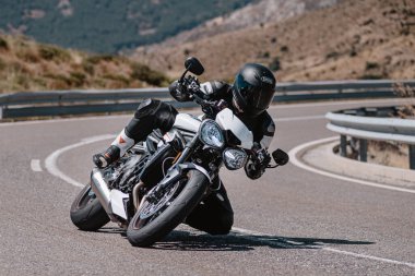 Motorsikletinde oturan bir adam, dağ yolunda keskin bir dönüş yapıyor. Fotoğraf Ağustos 2020 'de Avila şehrinde çekildi.