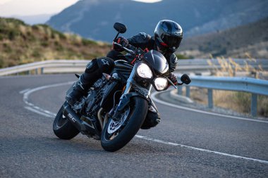 Motorsikletinde oturan bir adam, dağ yolunda keskin bir dönüş yapıyor. Fotoğraf Ağustos 2020 'de Avila şehrinde çekildi.