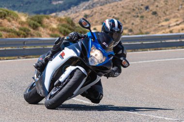 Motorcu motosikletiyle 10 Ağustos 2020 'de İspanya' nın Avila şehrinde bulunan Navalmoral limanında mavi gökyüzü ile güneşli bir günde motosikletine biniyor.