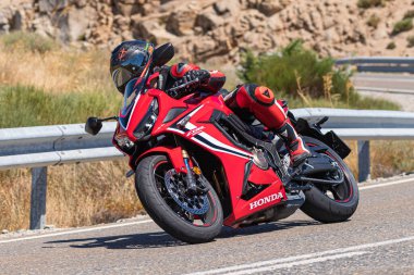 Motorcu motosikletiyle 10 Ağustos 2020 'de İspanya' nın Avila şehrinde bulunan Navalmoral limanında mavi gökyüzü ile güneşli bir günde motosikletine biniyor.