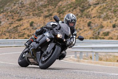 Motorcu motosikletiyle 10 Ağustos 2020 'de İspanya' nın Avila şehrinde bulunan Navalmoral limanında mavi gökyüzü ile güneşli bir günde motosikletine biniyor.