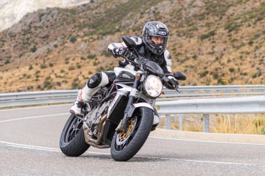 Motorcu motosikletiyle 10 Ağustos 2020 'de İspanya' nın Avila şehrinde bulunan Navalmoral limanında mavi gökyüzü ile güneşli bir günde motosikletine biniyor.