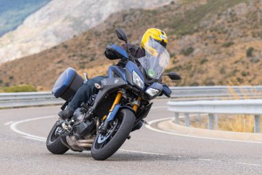 Motorcu motosikletiyle 10 Ağustos 2020 'de İspanya' nın Avila şehrinde bulunan Navalmoral limanında mavi gökyüzü ile güneşli bir günde motosikletine biniyor.