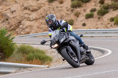 Motorcu motosikletiyle 10 Ağustos 2020 'de İspanya' nın Avila şehrinde bulunan Navalmoral limanında mavi gökyüzü ile güneşli bir günde motosikletine biniyor.