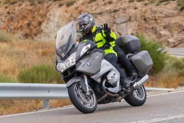Motorsikletinin üstünde oturan, limanda yüksek hızda gezen ve güneşli bir günde viraj alan bir adam. Fotoğraf Temmuz 2020 'de İspanya' nın Avila kentindeki Navalmoral de la Sierra kasabasında çekildi.