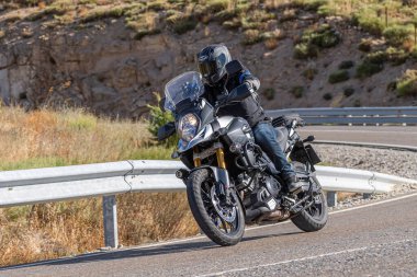 22 Ağustos 2020 'de İspanya' nın Avila şehrinde çekilen ve Navalmoral limanı adı verilen virajlı bir yolda motosikletine binen bir adam.