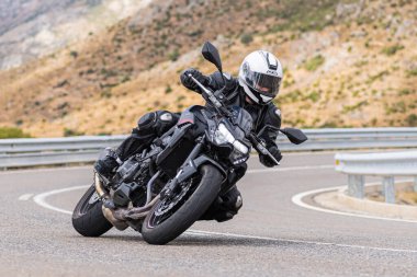 22 Ağustos 2020 'de İspanya' nın Avila şehrinde çekilen ve Navalmoral limanı adı verilen virajlı bir yolda motosikletine binen bir adam.