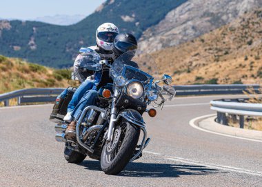Motorcu, Avila limanında bir viraj alıyor güneşli bir gün ve dağ gibi bir geçmişi var. Fotoğraf 29 Ağustos 2020 'de Navalmoral de la Sierra, Avila, İspanya' da çekildi.