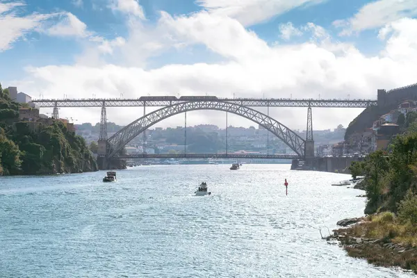 Luiz I Porto şehrinin köprüsü, ön planda renkli arka plan ve nehir kıyısında çeşitli tekneler var.