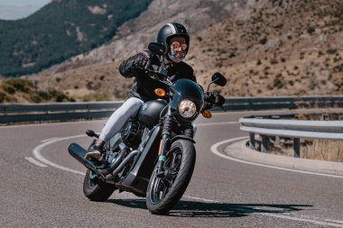 Makinesinde motosikletli, keskin bir virajda yolda seyahat ediyor. Fotoğraf: Navalmoral de la Sierra-Avila, İspanya 'da Ağustos 2022' de çekilmiştir..