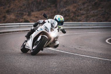 Makinesinde motosikletli, keskin bir virajda yolda seyahat ediyor. Fotoğraf: Navalmoral de la Sierra-Avila, İspanya 'da Ağustos 2022' de çekilmiştir..